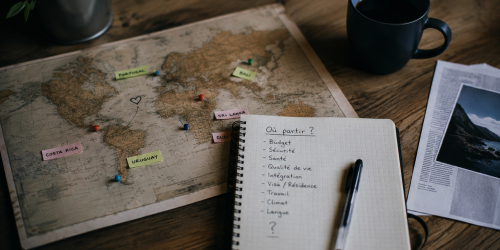 Carnet de notes et carte annotée pour comparer différentes destinations d’expatriation selon le budget, la santé, la sécurité et la qualité de vie.